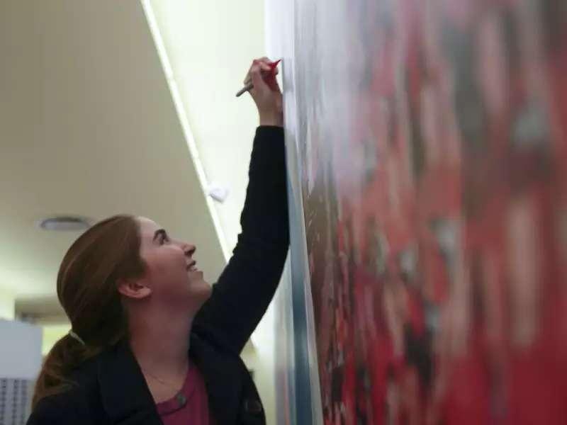 close up of a woman writing on a blackboard